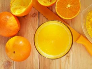 Naranjas cortadas junto a un vaso lleno de zumo