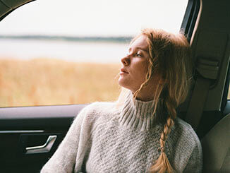 Mujer mirando a través de la ventana de un coche